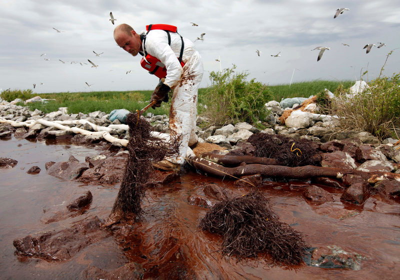 A worker picks up blobs of oil with absorbent snare near the Gulf of Mexico in Plaquemines Parish, Louisiana, immediately following the 2010 accident. Photo: AP